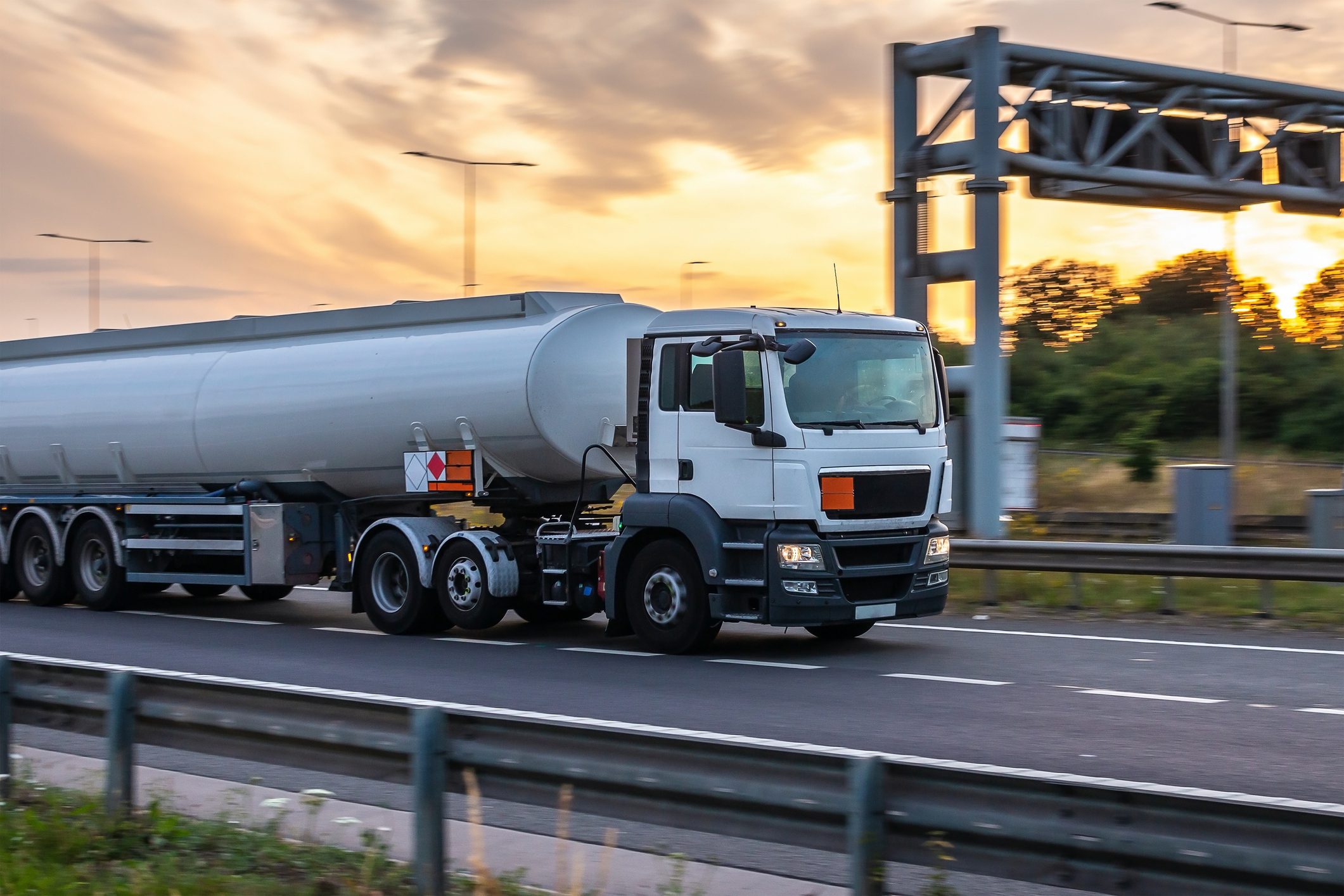 Tanker truck in motion on the motorway with orange sky in the background
