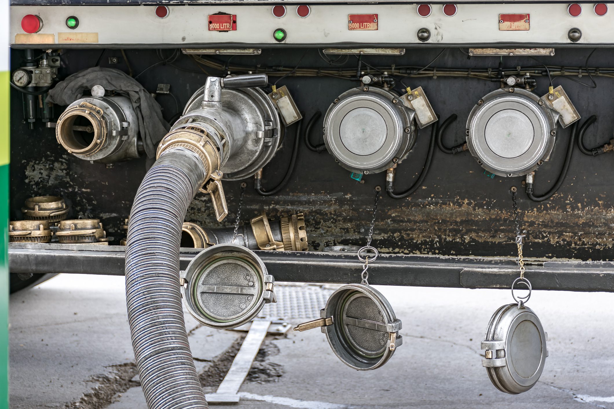 Fuel tanker unloading diesel at a service station,with the hose connected from the truck to the mouth of the tank on the ground
