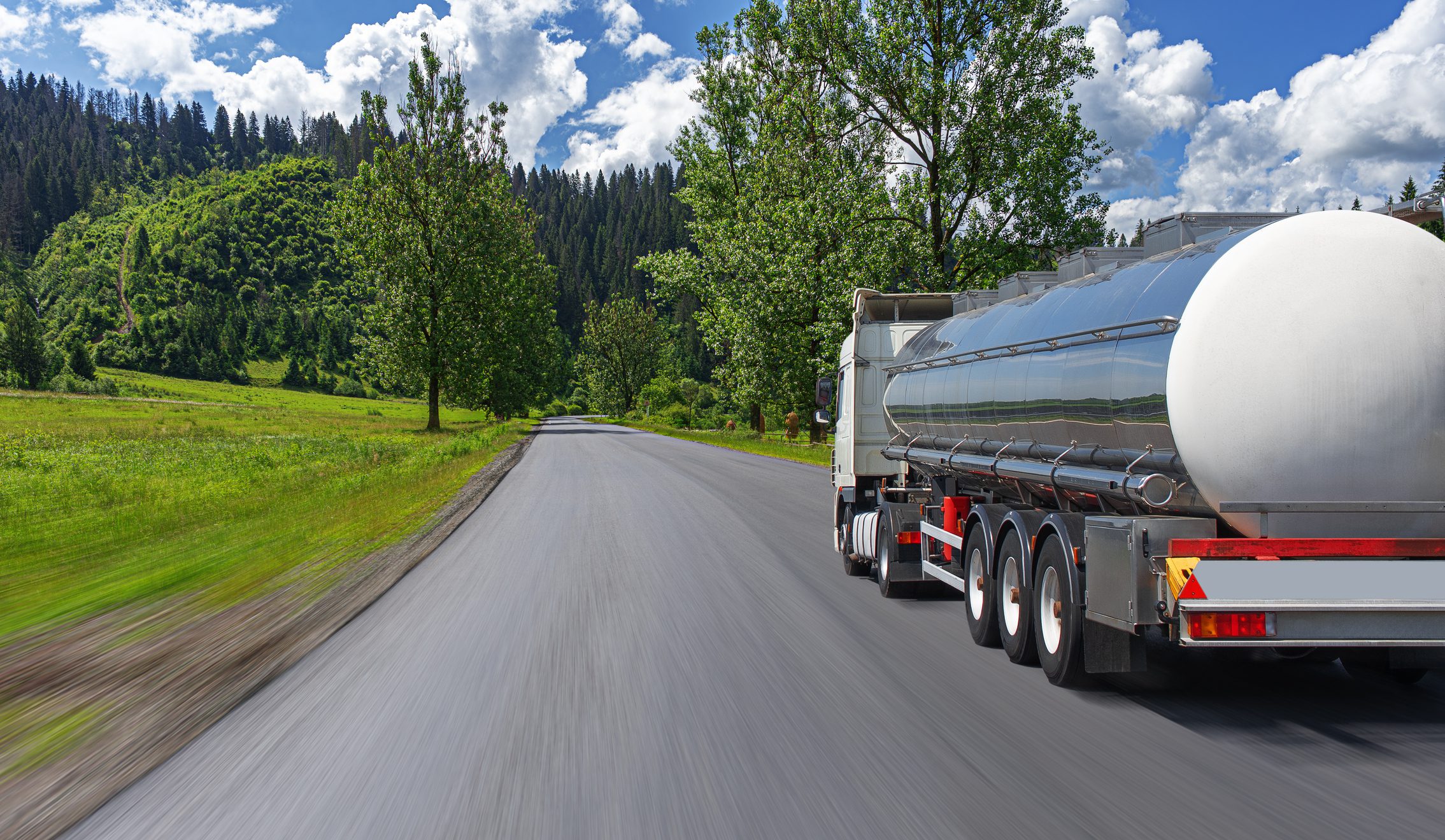 Fuel truck on a picturesque road. A silver tank truck transports fuel.
