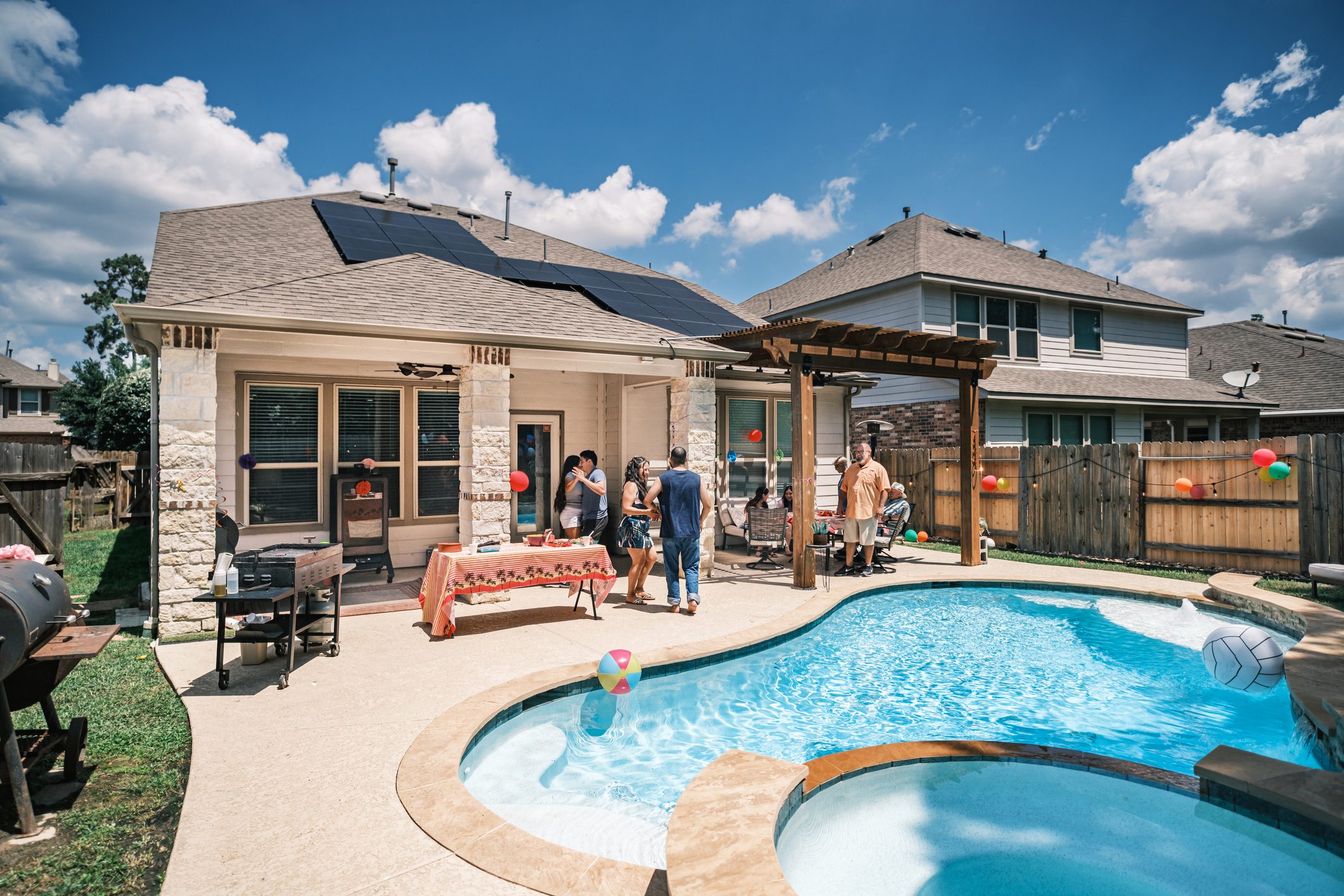 Mexican American family having a party in backyard of sustainable home with solar panels on the roof. Suburb area of Houston, Texas.